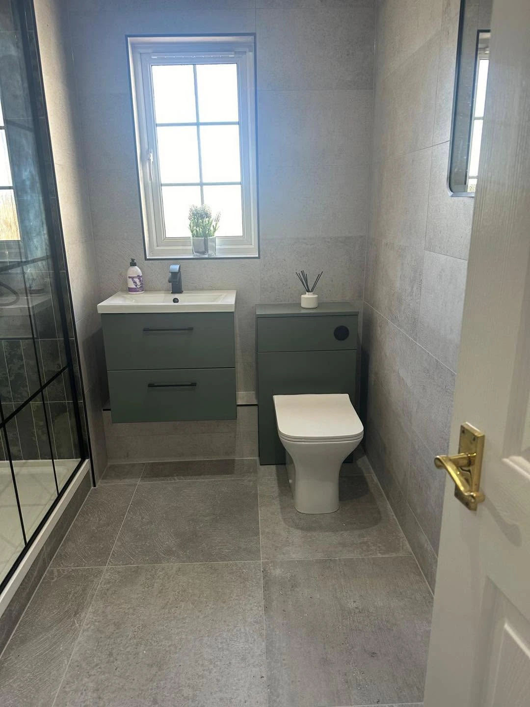 Finished shower room with green vanity, concealed-cistern toilet and glazed shower enclosure