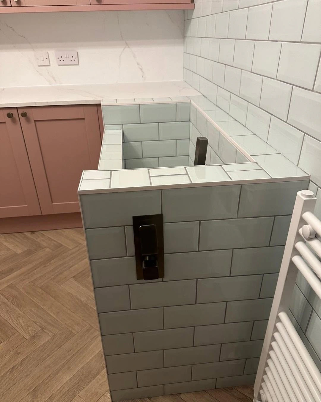 Tiled wash area with dark wall fitting and fitted utility cabinetry