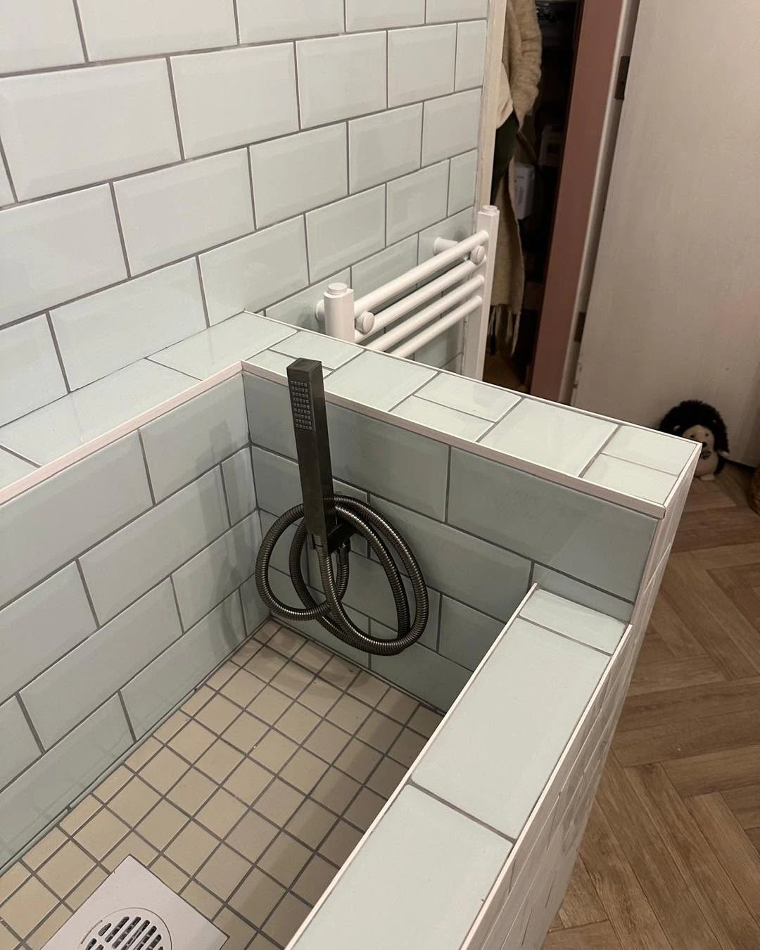 Close view inside the tiled wash area with flexible shower fitting