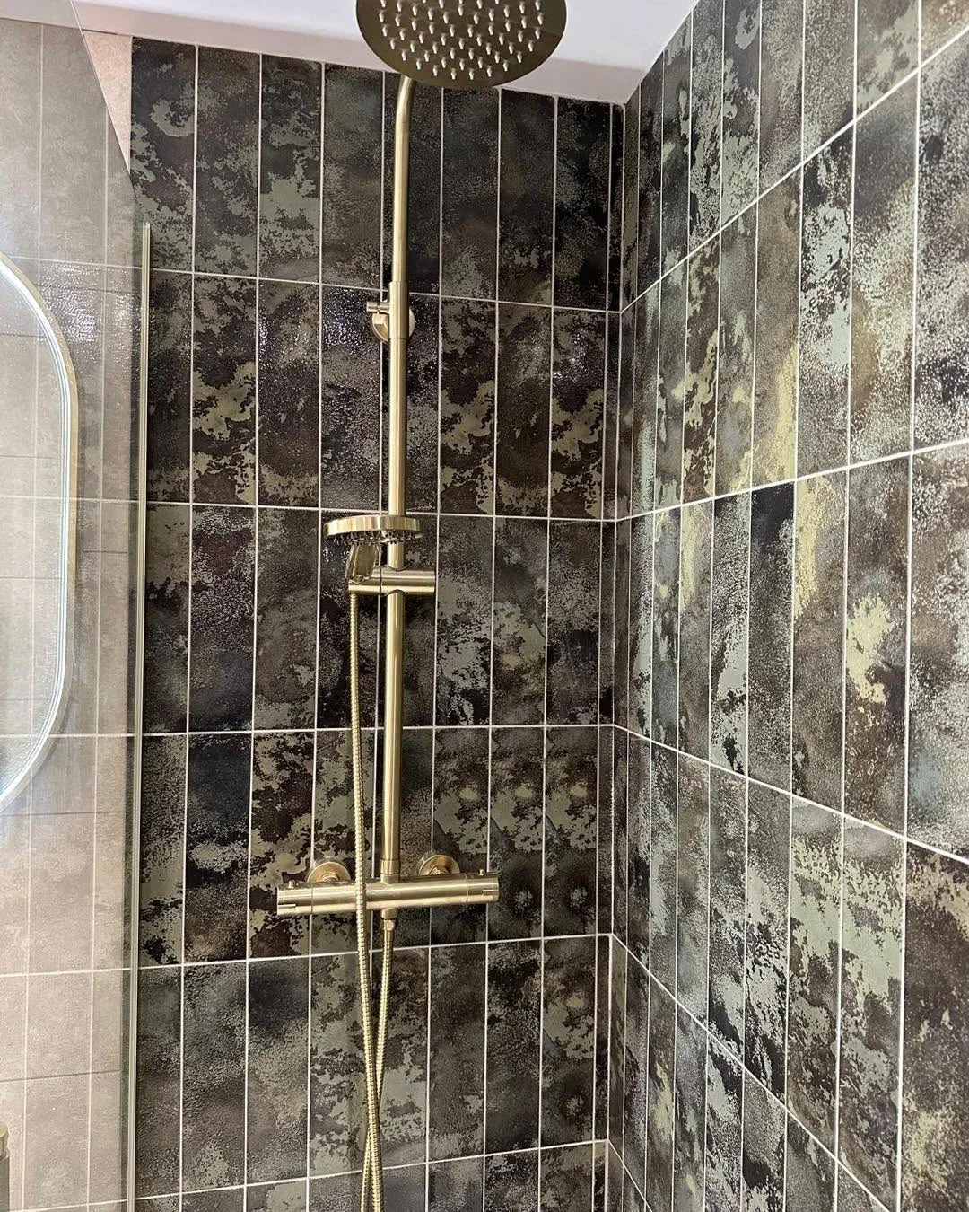 Bronze rainfall shower against dark textured feature tiles
