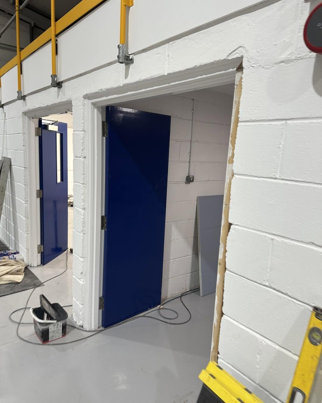 Newly fitted blue doorways within the finished blockwork wall