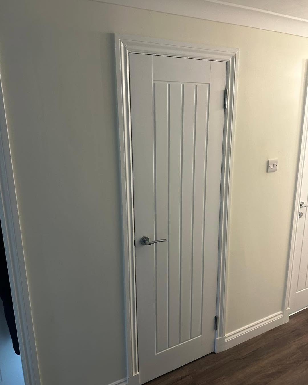 White vertical-panel internal door with fitted trim and chrome lever handle