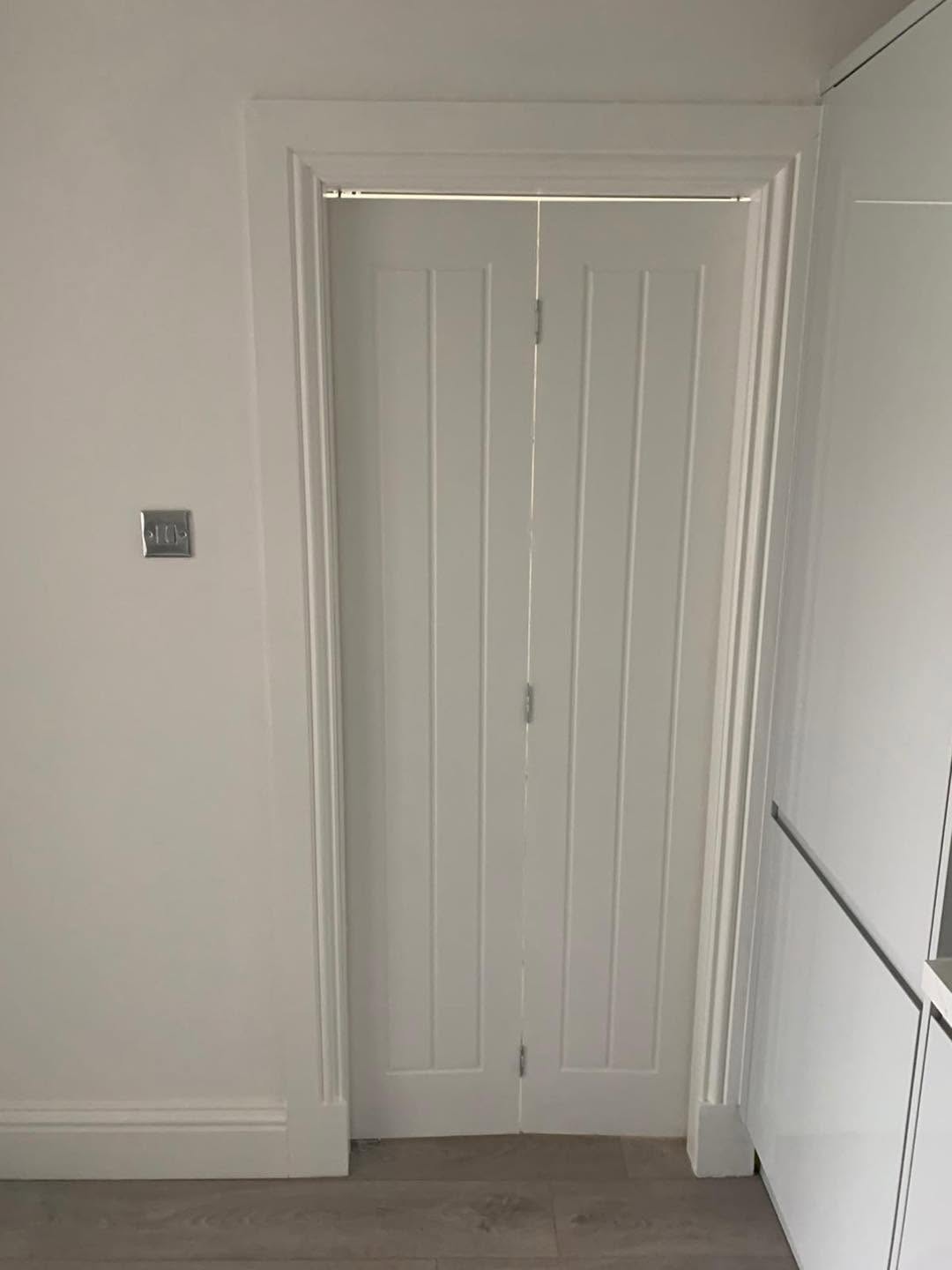 White folding internal doors fitted within detailed timber trim