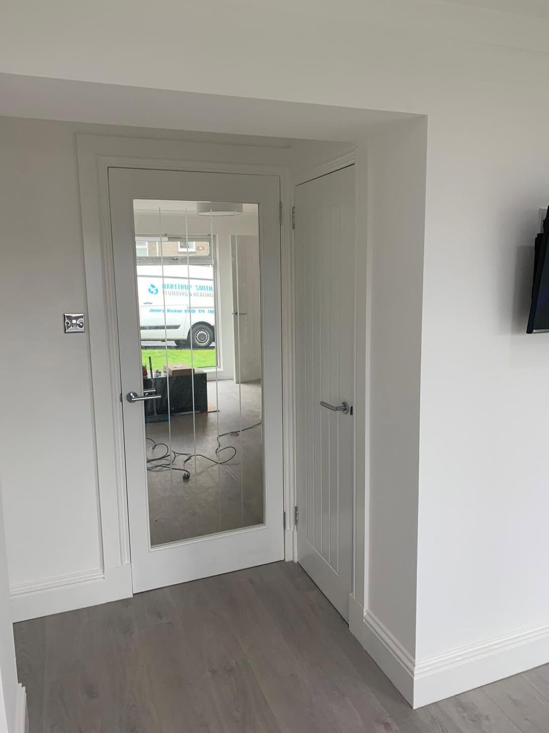 Glazed and panelled white internal doors within a finished hallway