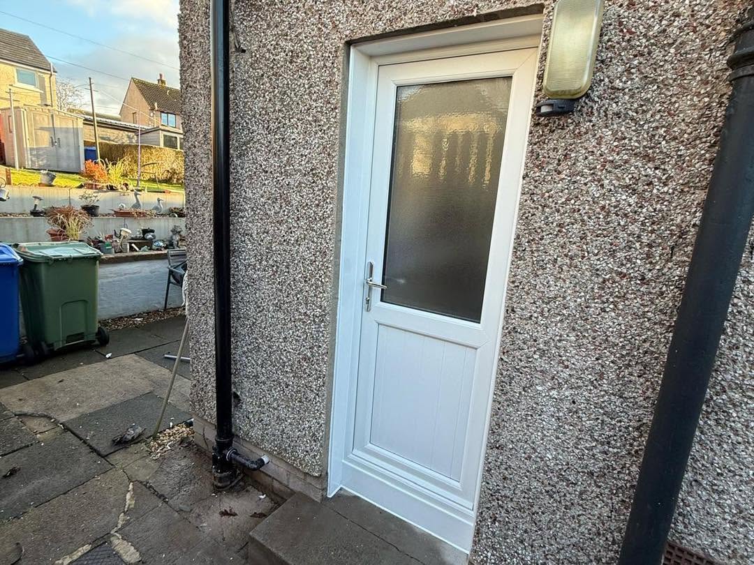White external rear door with obscured glazing fitted to a rendered property